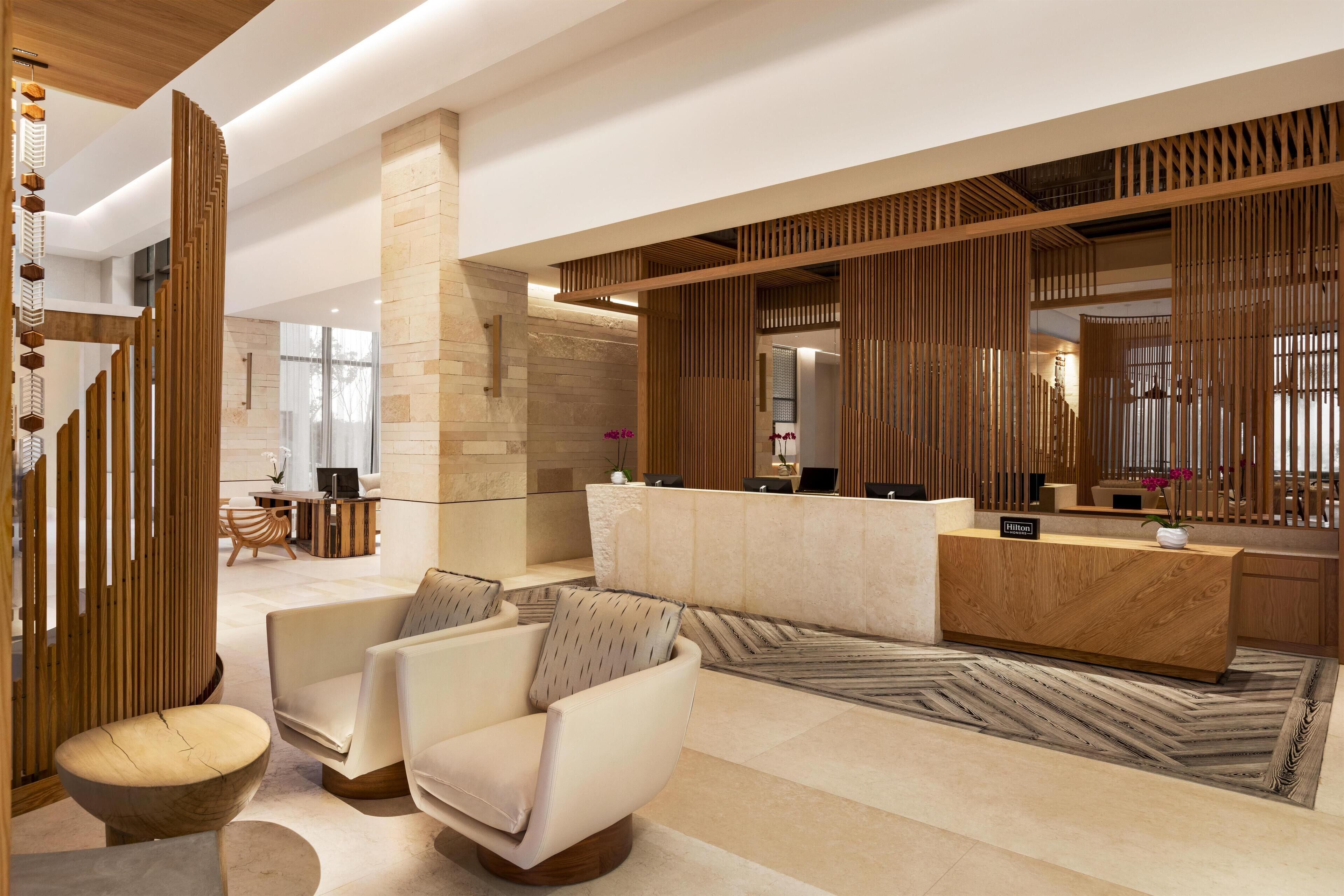 A modern hotel lobby with a reception desk, seating area, and decorative wooden panels.
