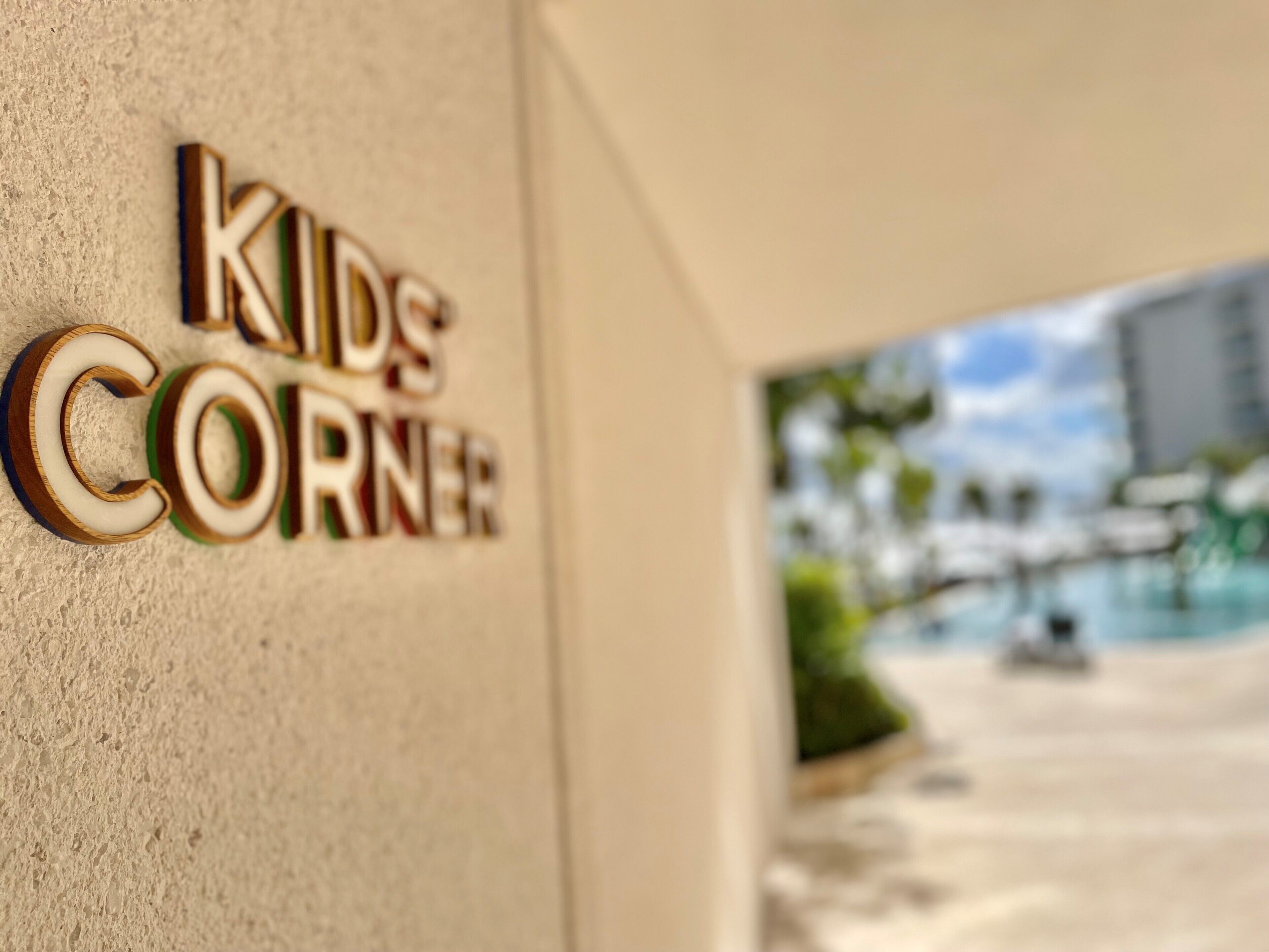 A sign for "Kids Corner" on a textured wall.