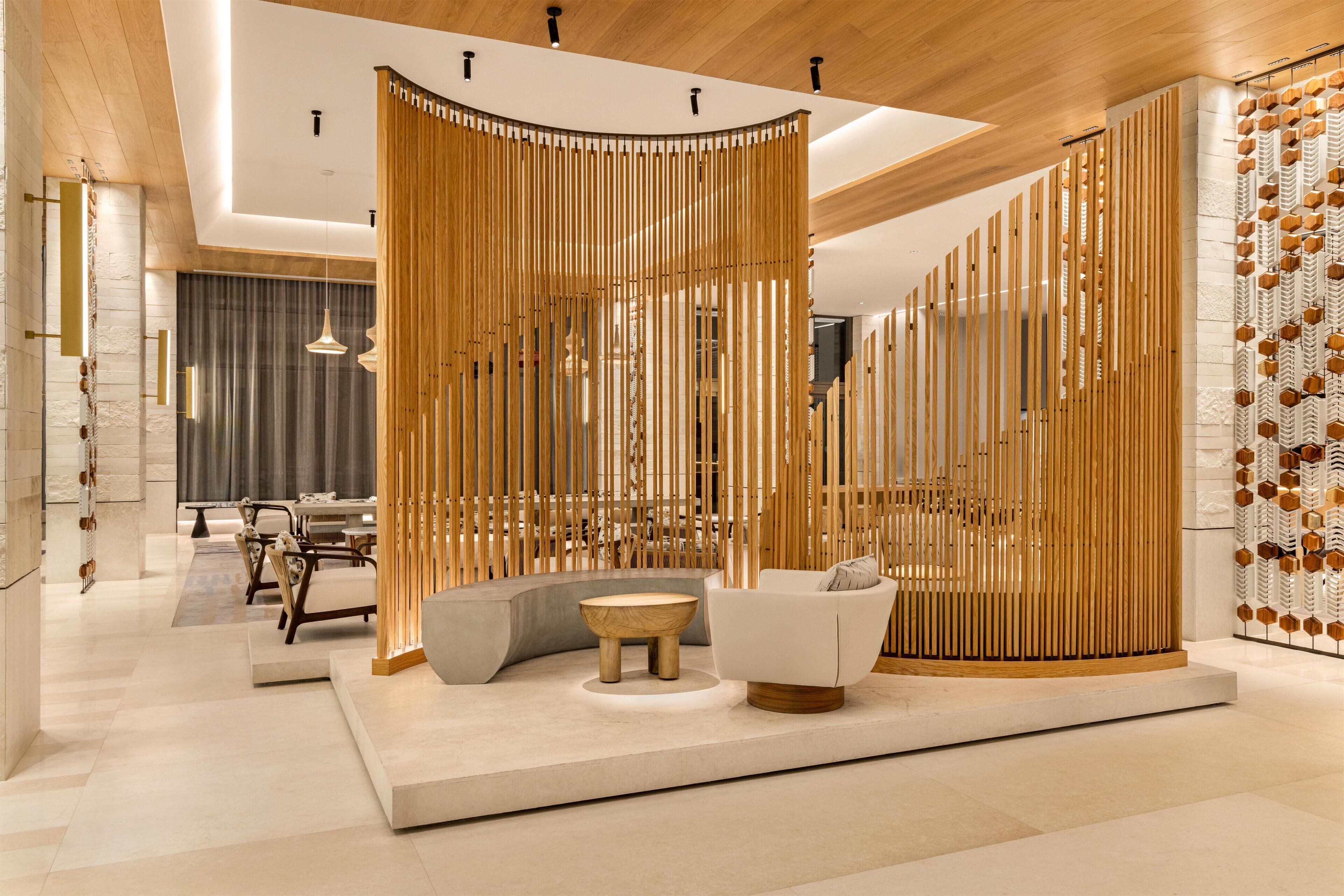 A modern interior with a wooden ceiling, a seating area with a sofa and a round table, and a decorative wall with vertical wooden slats.