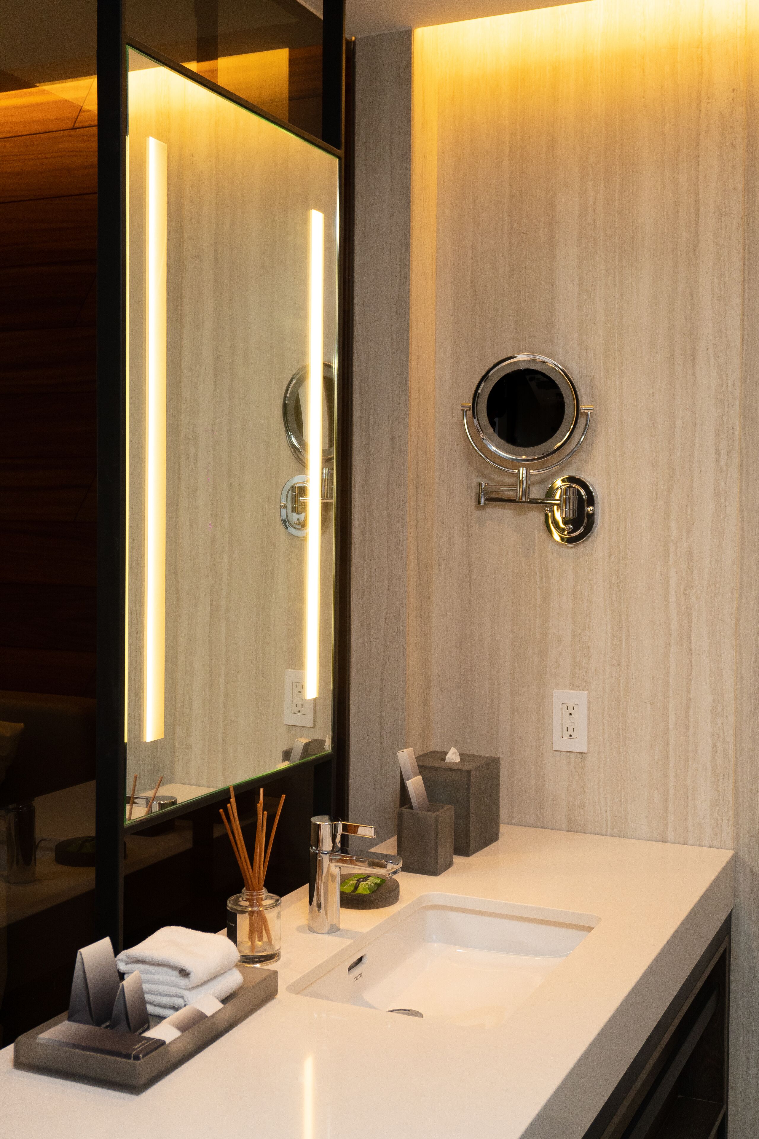 Un bagno moderno con un ampio specchio, un lavabo rotondo e un piano vanità.