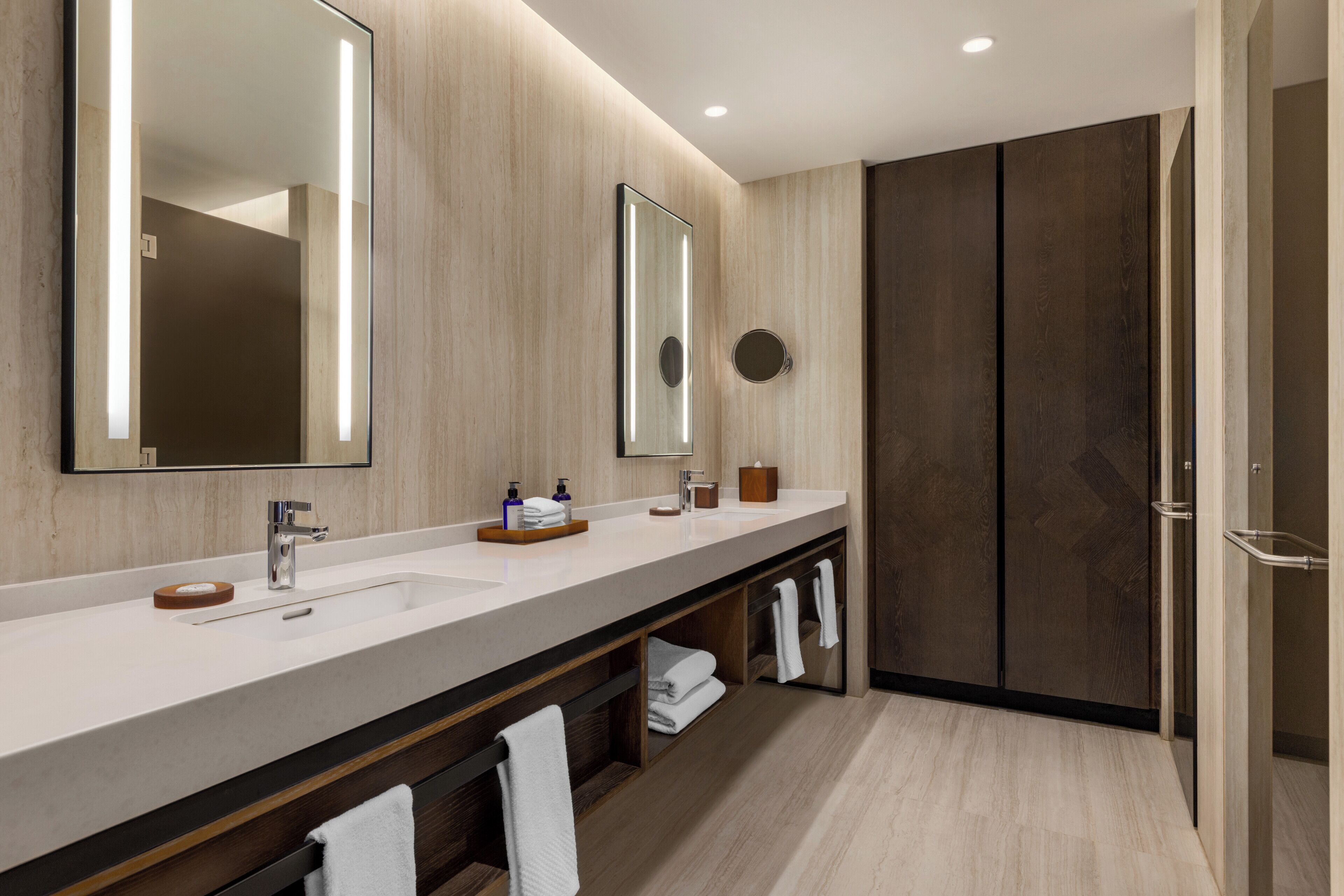 A modern bathroom with a long vanity, two mirrors, a sink, and a walk-in shower.