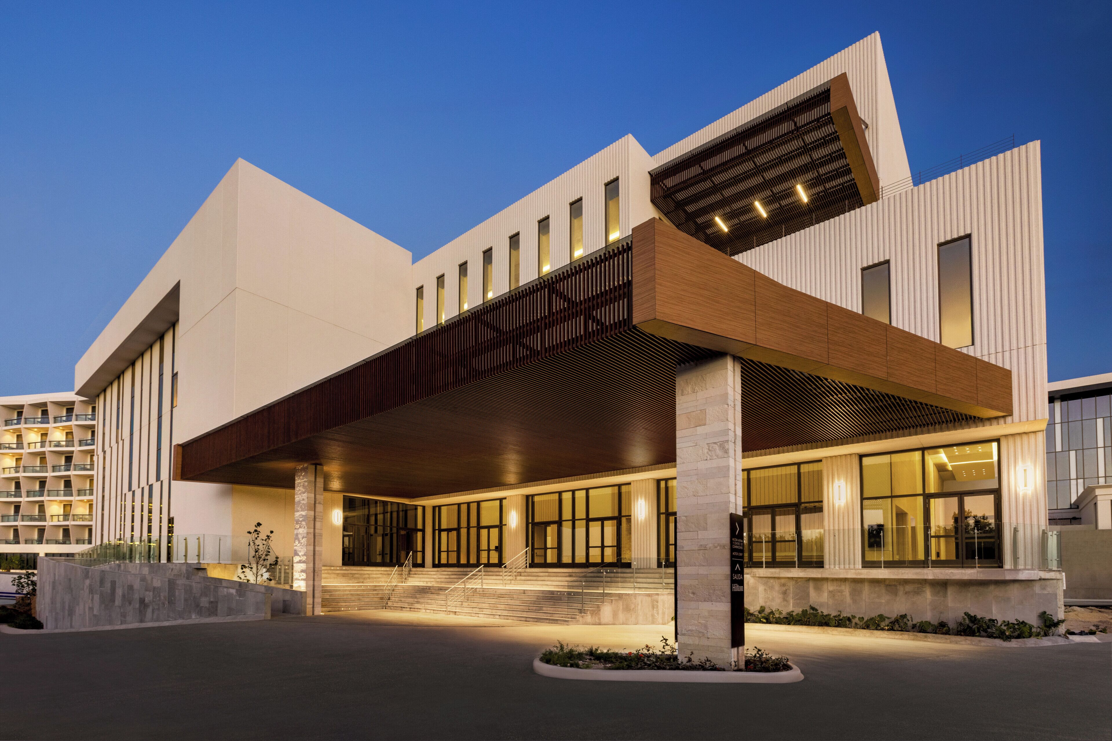 A modern hotel with a prominent entrance, large windows, and a covered outdoor area.