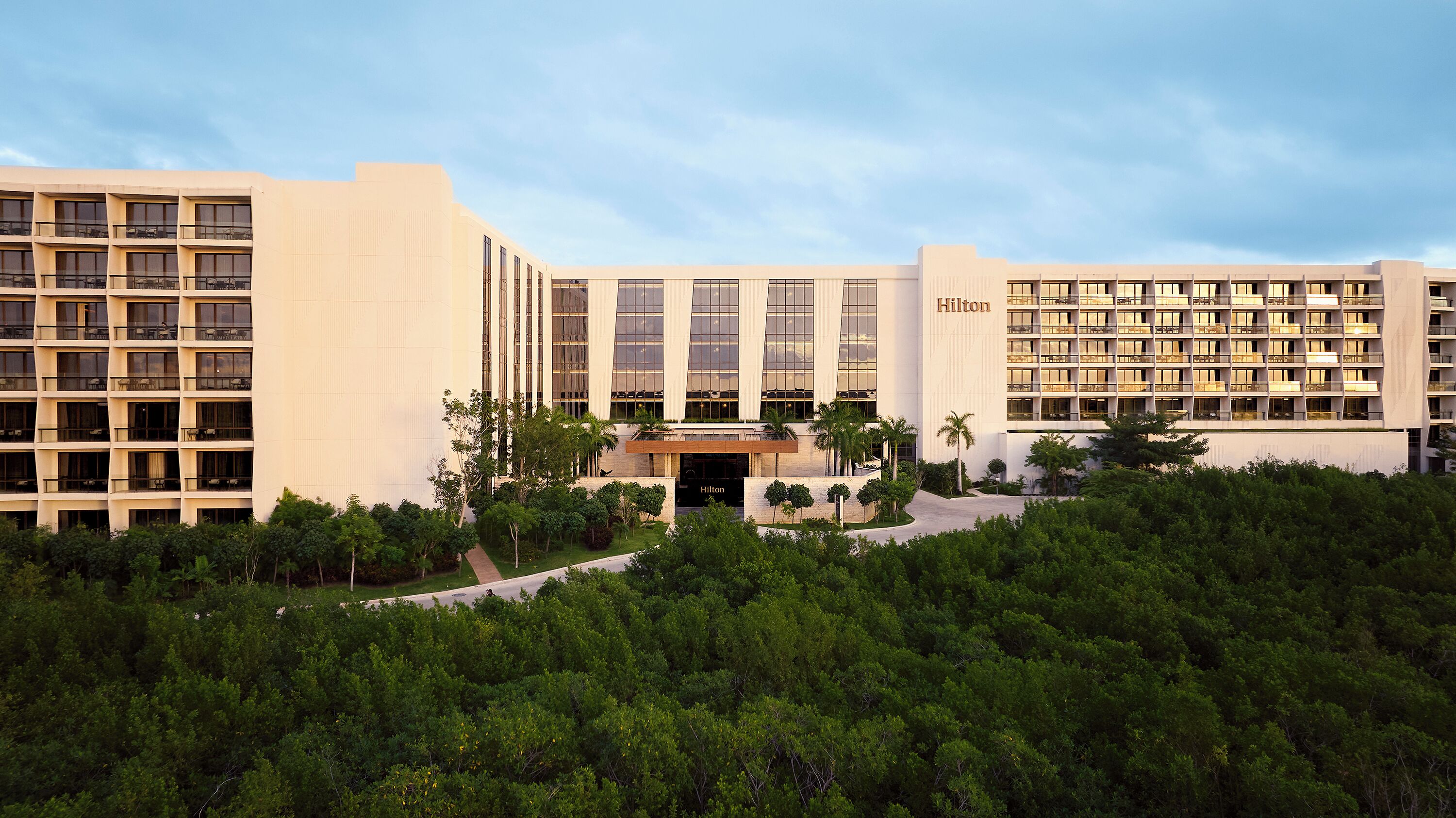 A multi-story hotel with a modern design, featuring a prominent entrance and multiple balconies.