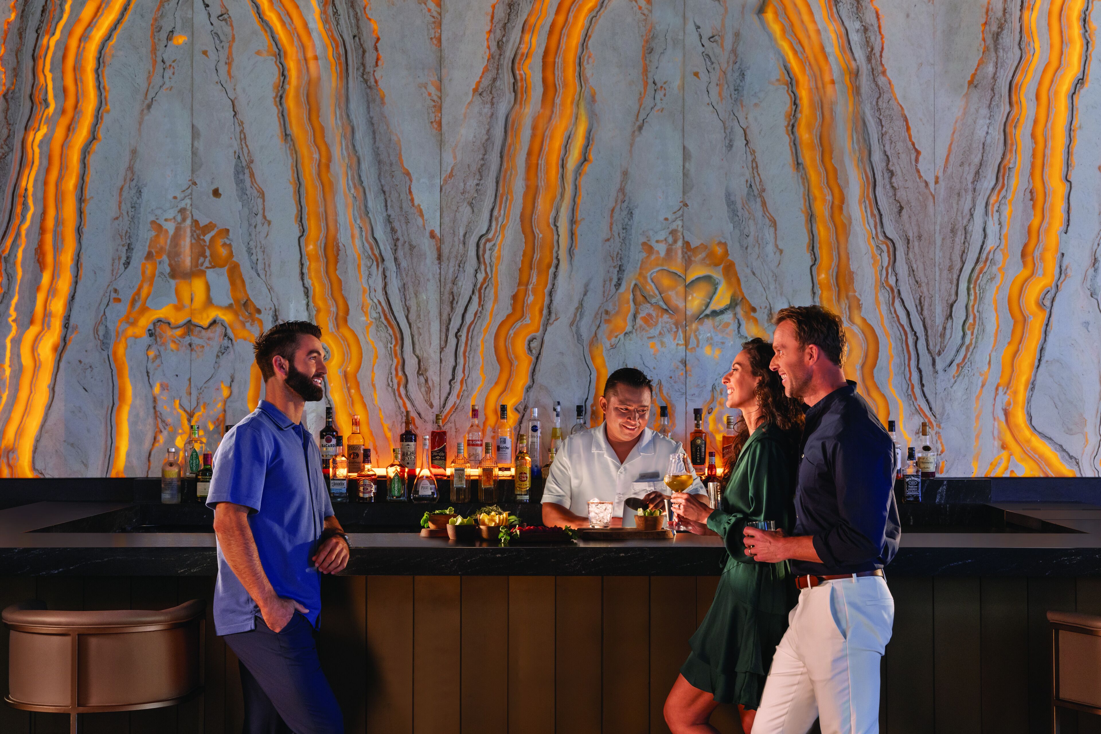 A bar area with a marble wall and a bartender.