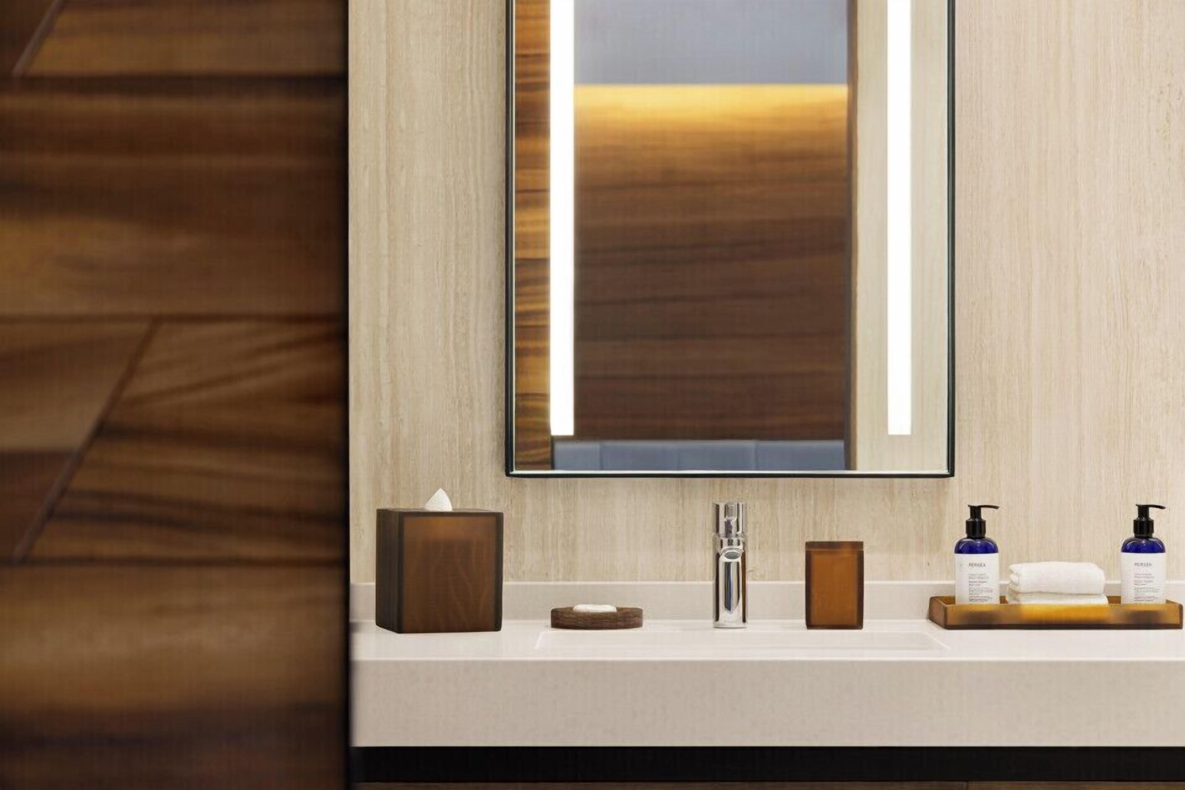 A modern bathroom with a large mirror, a sink, and toiletries.