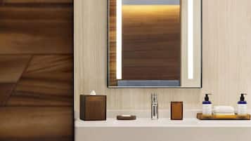 A modern bathroom with a large mirror, a sink, and toiletries.
