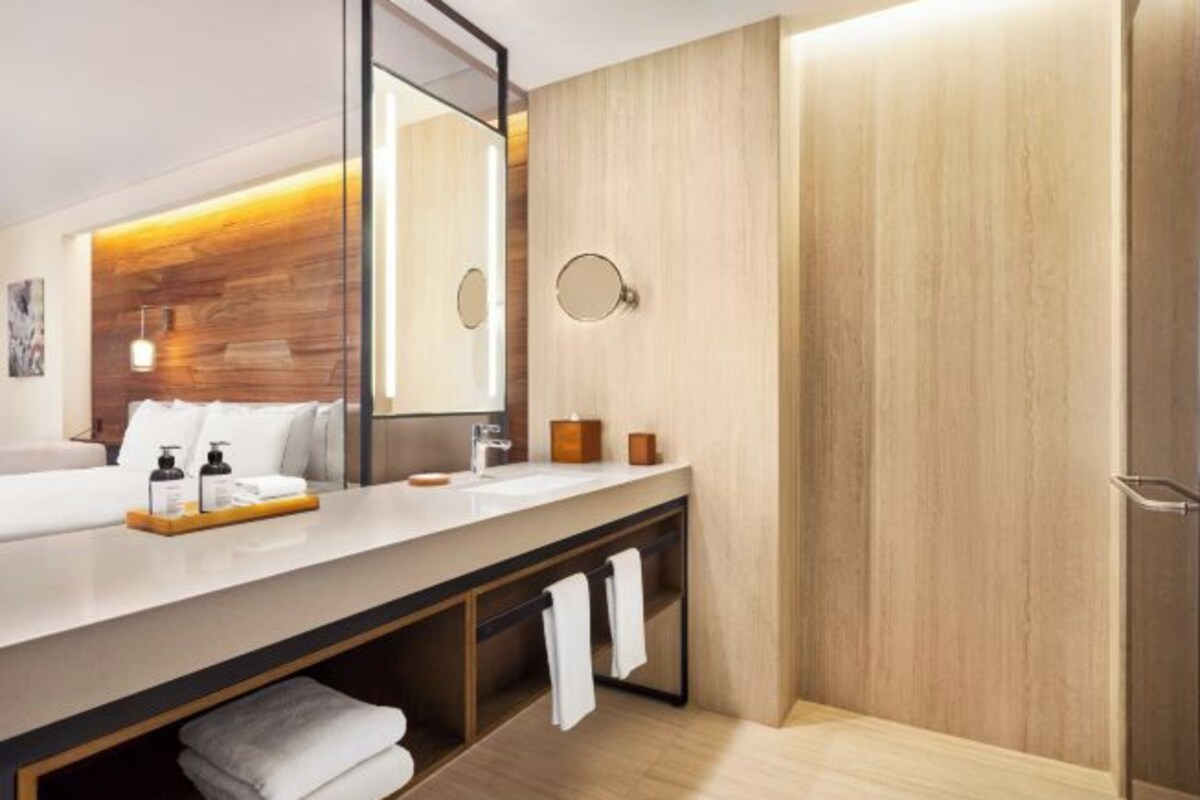 A modern bathroom with a wooden vanity, a large mirror, and a towel rack.