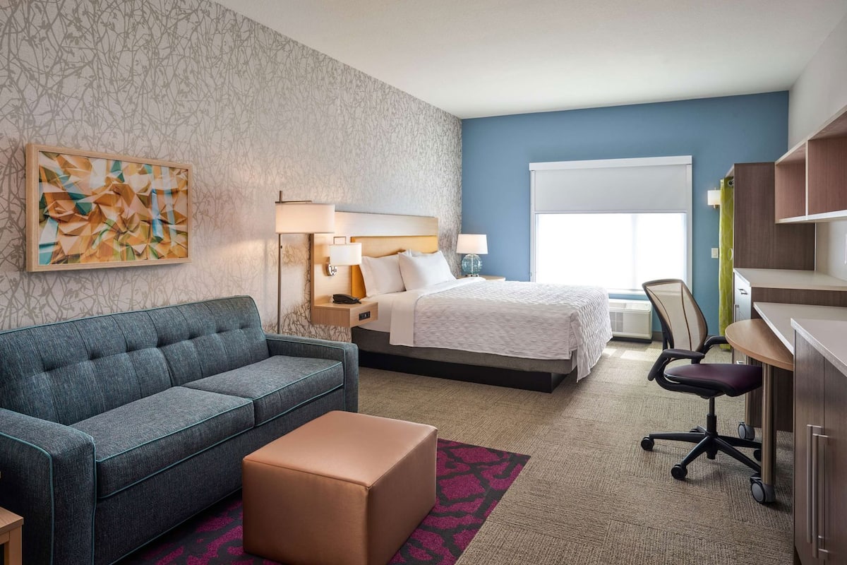 Ein Hotelzimmer mit Bett, Sofa, Schreibtisch und Stuhl.