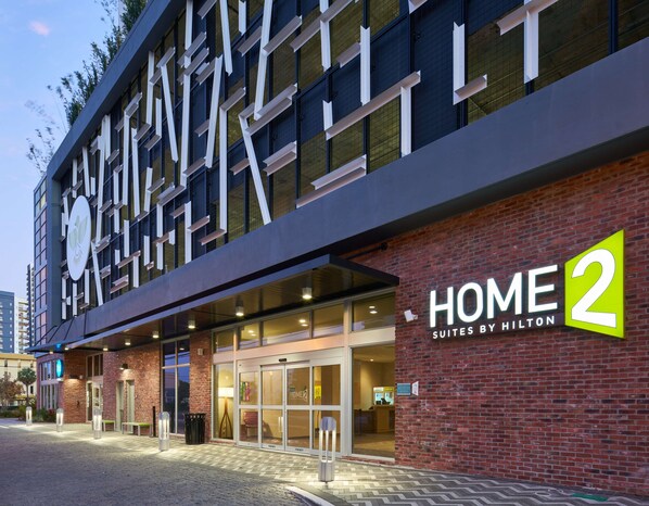 L’entrée d’un hôtel au design moderne, avec une enseigne « HOME 2 » bien visible et une façade en briques.