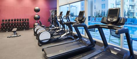 Une salle de sport équipée de tapis de course, de vélos d’appartement et d’haltères.