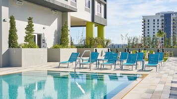 Una piscina al aire libre, sillones reclinables de piscina