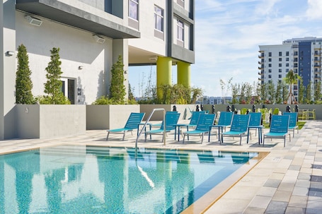 Una piscina al aire libre, sillones reclinables de piscina