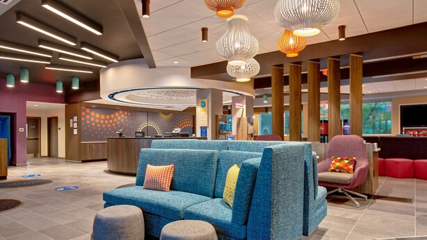 Eine moderne Lobby mit einem blauen Sofa, einem Empfangstresen und einem großen Fenster.