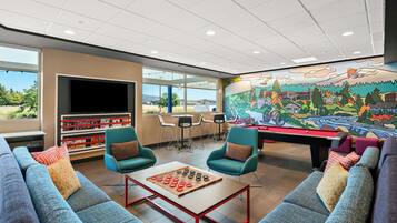 Un moderno espacio lounge con asientos cómodos, una mesa de billar y un mural grande.