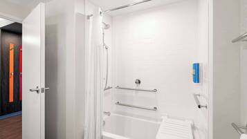 A modern bathroom with a white bathtub, grab bars, and a showerhead.
