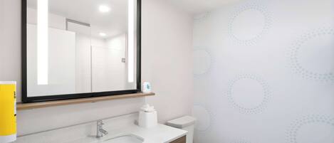 A modern bathroom with a large mirror, a sink, and a toilet.