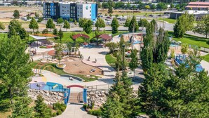A modern building with a blue and white facade, surrounded by a park with playgrounds and walking paths. - Tru By Hilton Spokane Valley, WA (Spokane Valley)