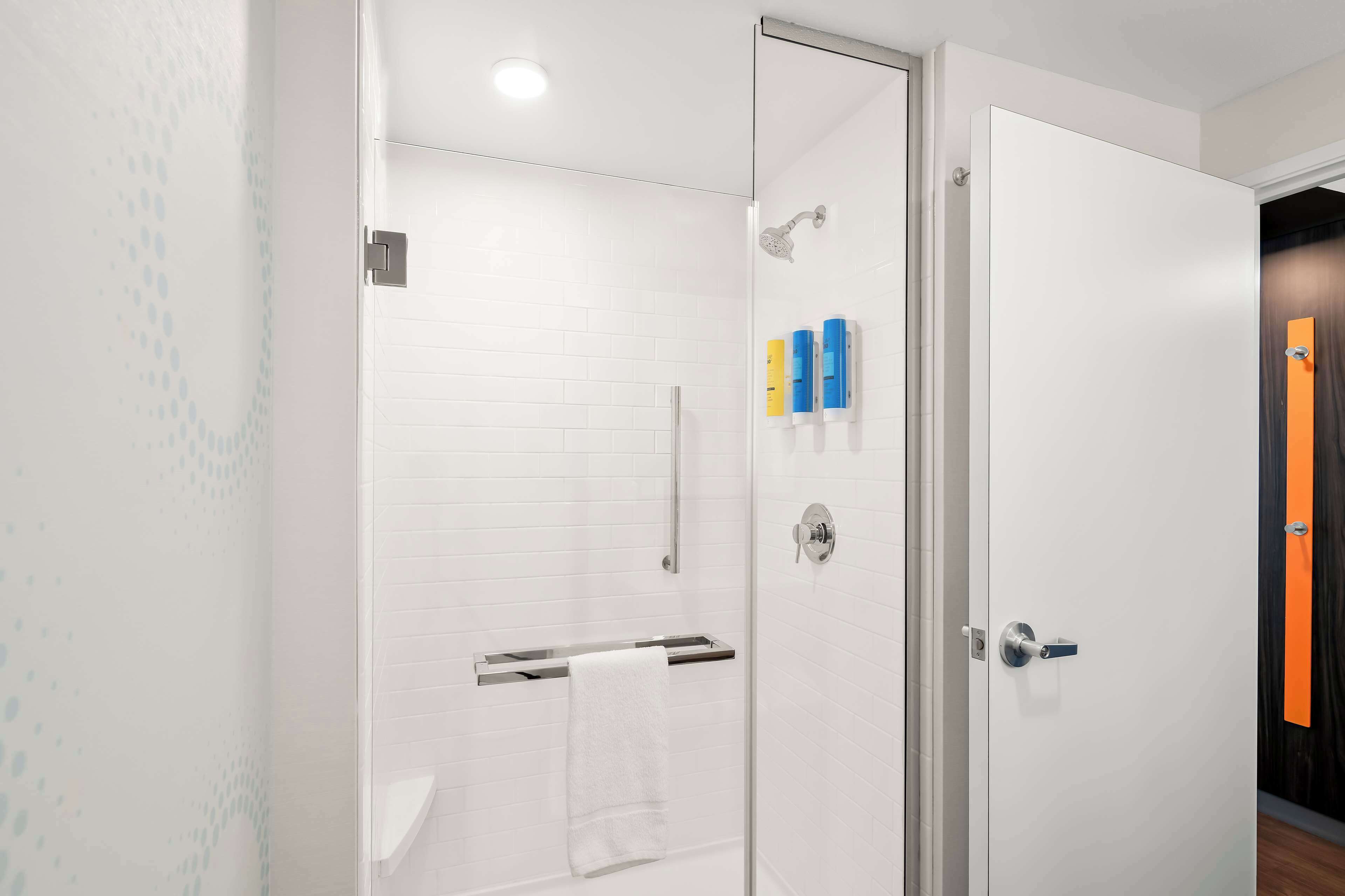 A modern bathroom with a glass shower enclosure, white tiled walls, and a white towel hanging on a rack.