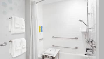 A modern bathroom with a white bathtub, grab bars, and a towel rack.