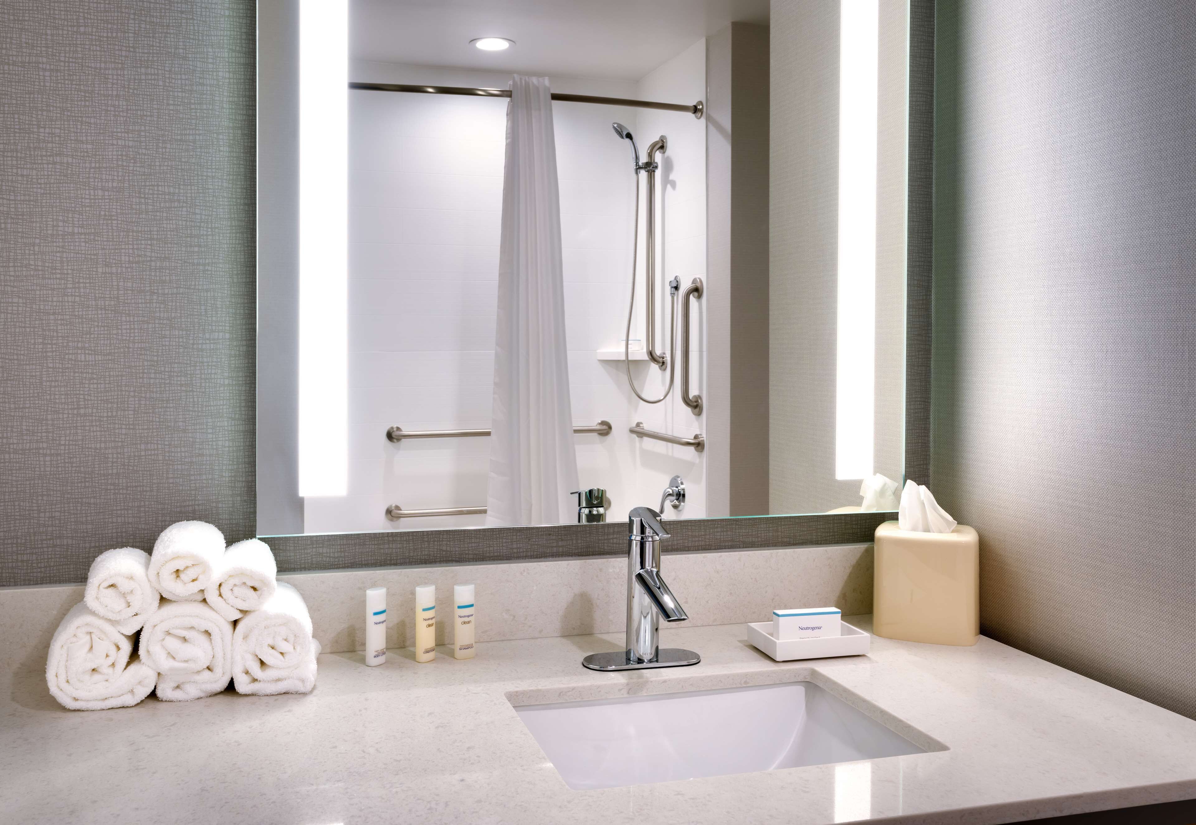 A modern bathroom with a sink, mirror, and shower.