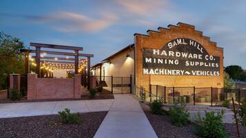 A building with a sign reading "Sam Hill Hardware Co. Mining Supplies Machinery Vehicles".