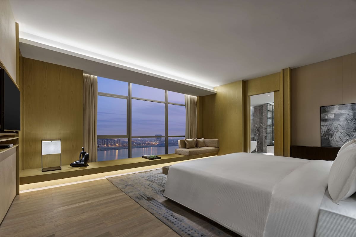 Une chambre d’hôtel moderne dotée d’un grand lit, d’un coin salon avec vue et d’une télévision.