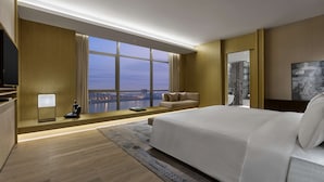 Une chambre d’hôtel moderne dotée d’un grand lit, d’un coin salon avec vue et d’une télévision.