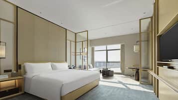 A modern hotel room with a large bed, a television, and a city view.