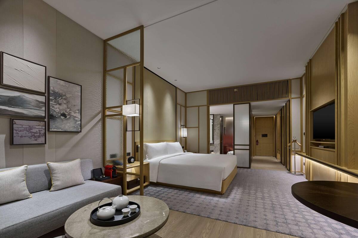 Une chambre d ’hôtel moderne équipée d’un lit, d’un canapé et d’un coin repas avec un plateau.