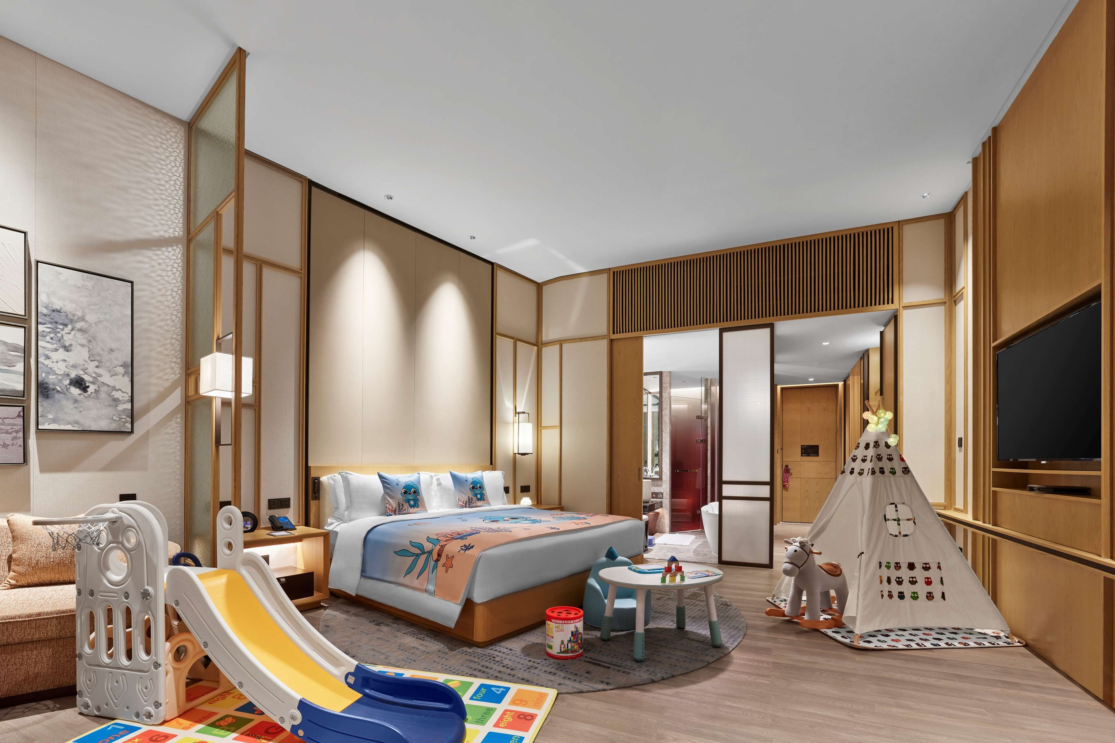 A hotel room with a bed, a play area, a small table, and a tent.