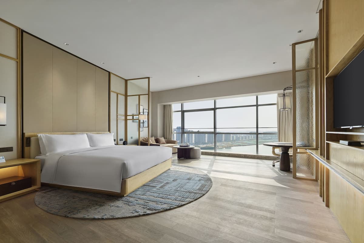 Une chambre d’hôtel moderne dotée d’un grand lit, d’un bureau, d’une télévision et offrant une vue sur la ville.