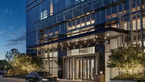 Un bâtiment moderne avec une façade en verre, une voiture garée devant et une entrée bien éclairée.