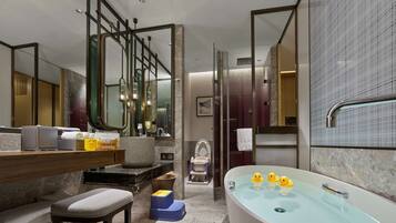 A modern bathroom with a large bathtub, a children's travel kit, a step stool, and a baby changing station.