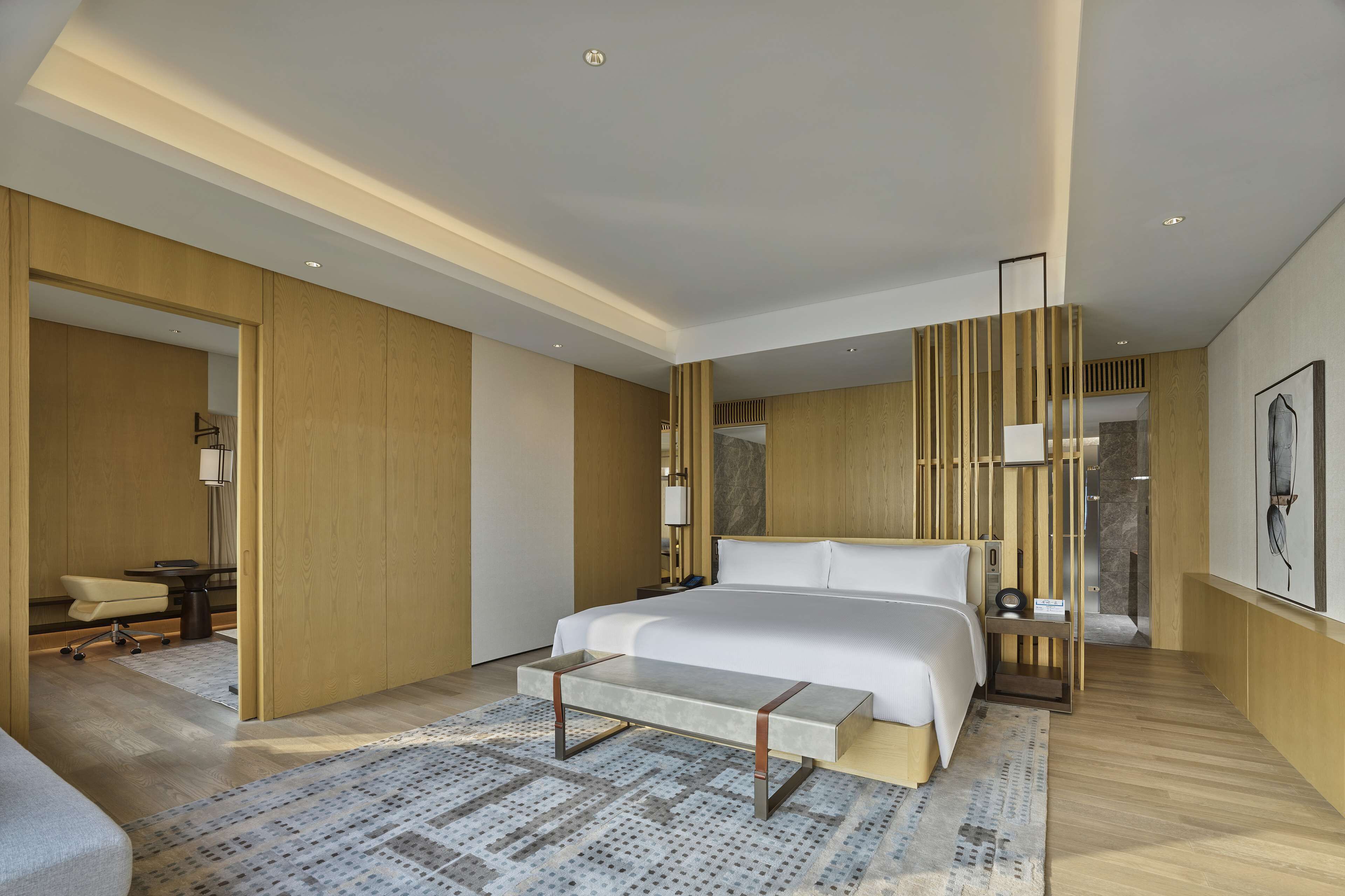 A modern hotel room with a large bed, a desk, and a chair.
