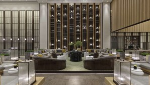 Un hall d’entrée moderne avec des canapés, une table basse centrale et un coin bar.
