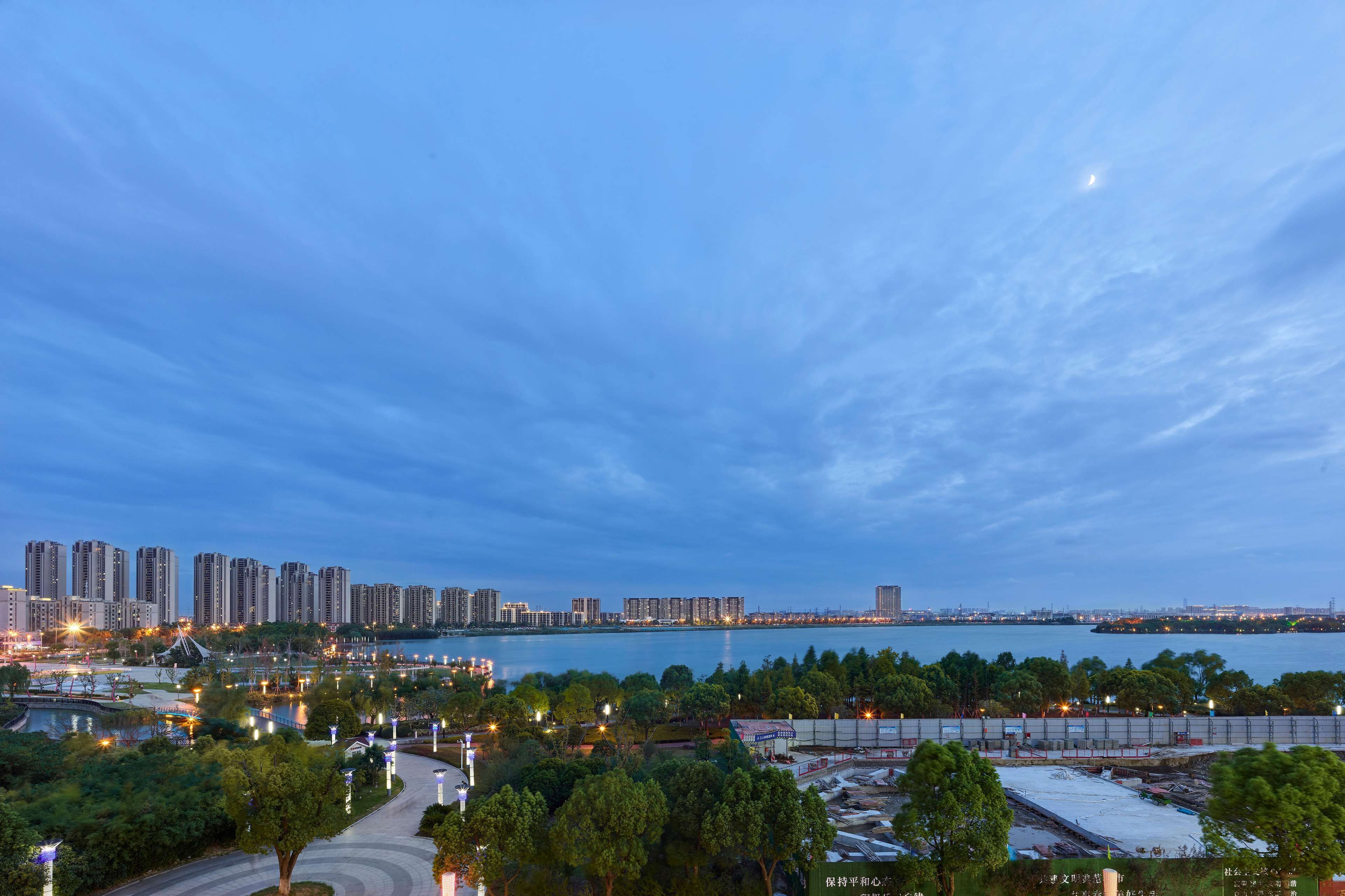 A cityscape with high-rise buildings, a waterfront, and a park area with trees and pathways.