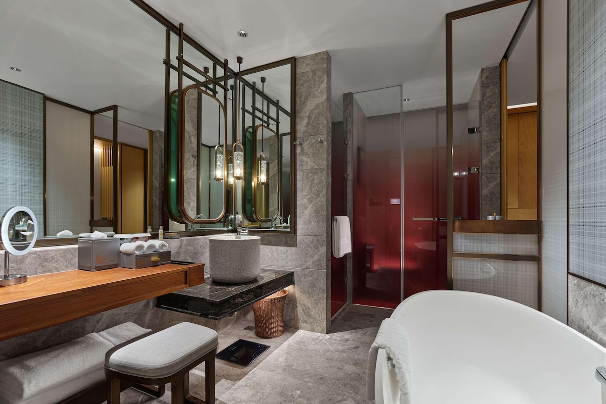 A modern bathroom with a large mirror, a vanity with a sink, a bathtub, and a shower area.