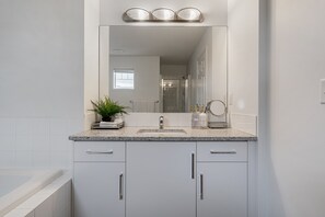A modern bathroom with a granite countertop, a large mirror, a sink, and a bathtub. - Evergreen Calgary Townhome — 3BR, Sleeps 6, Gas Fireplace, Free Parking (Calgary)