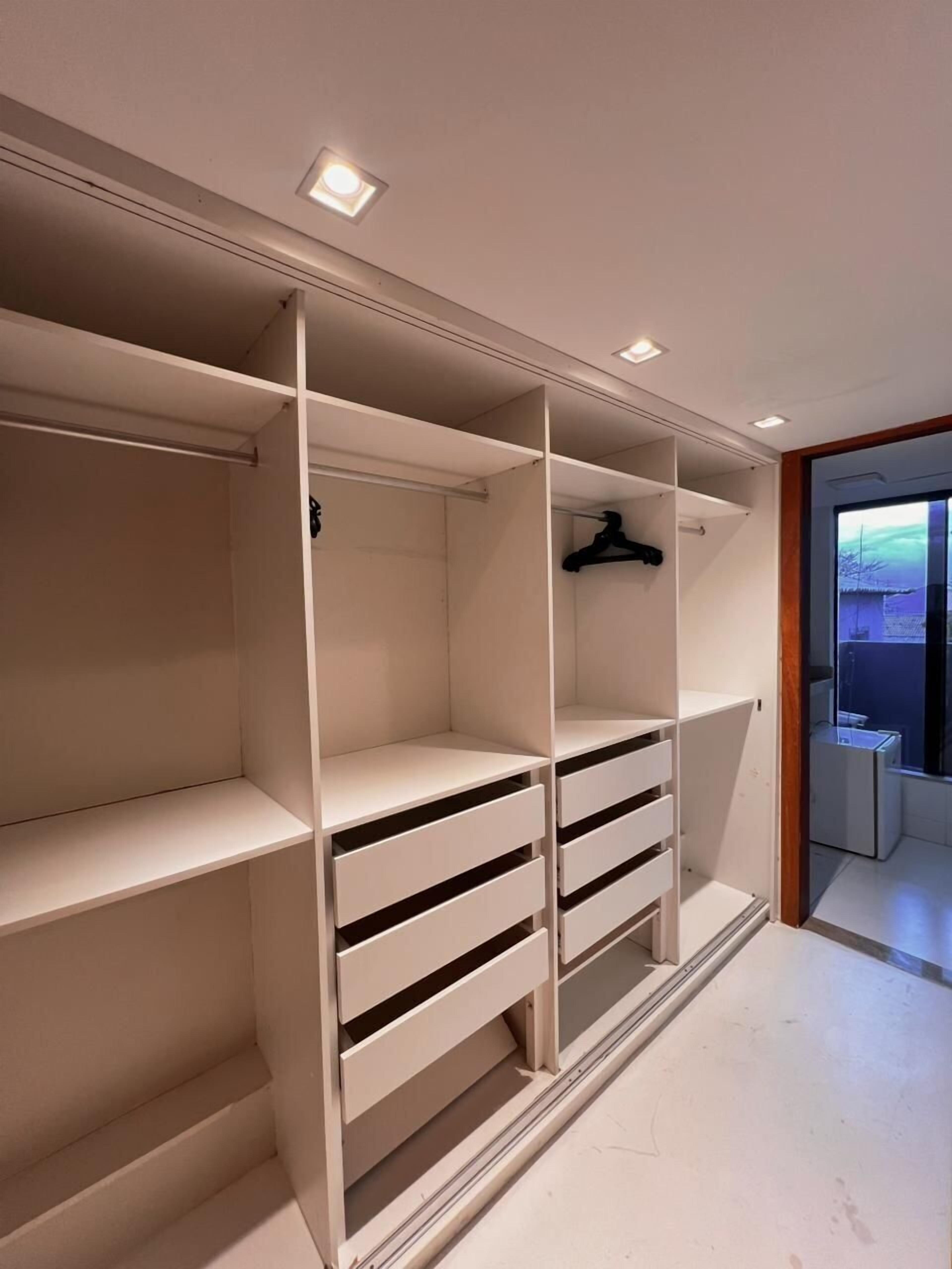 Ein moderner Kleiderschrank mit mehreren Einlegeböden, Schubladen und einer Kleiderstange, ausgestattet mit Einbauleuchten.