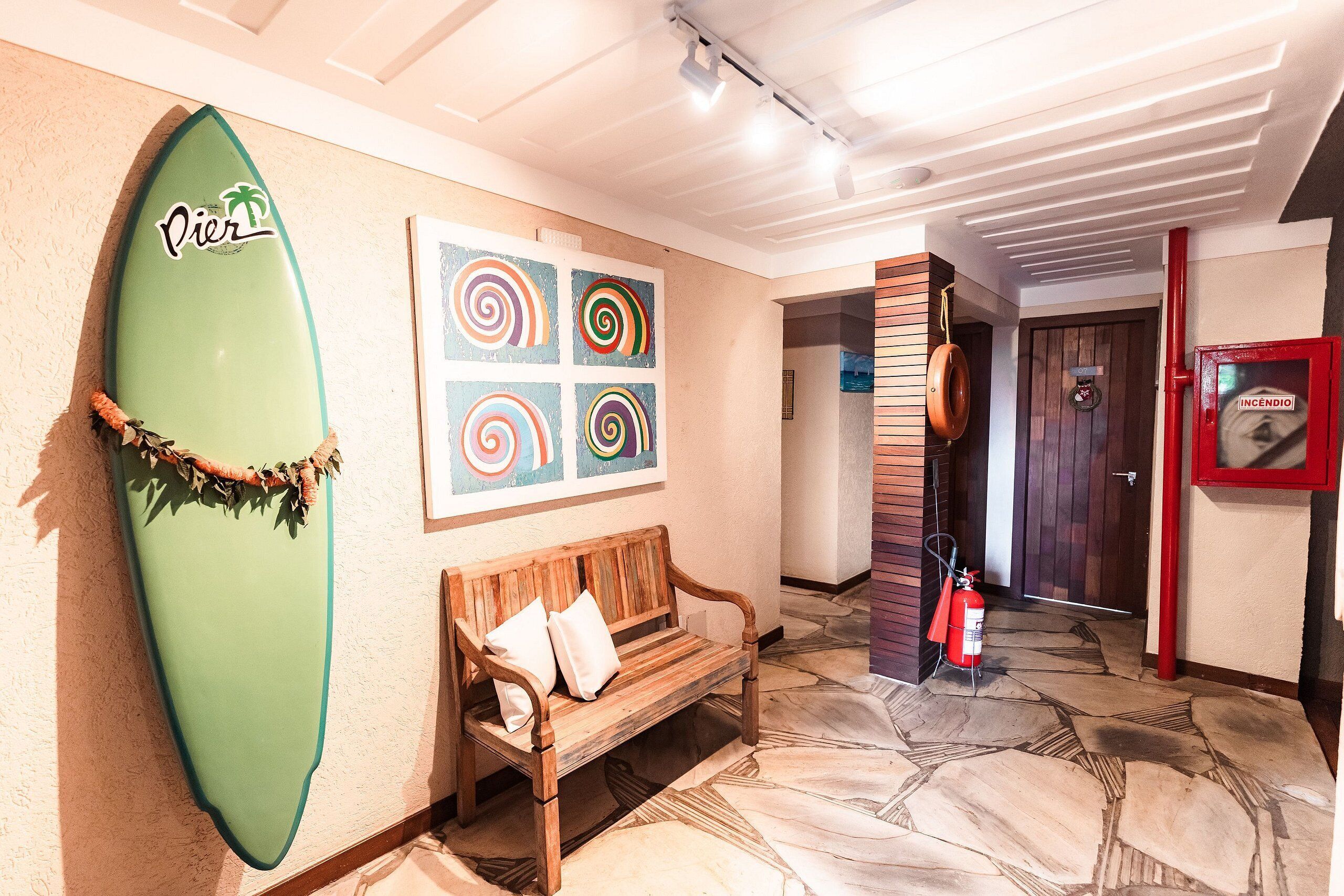 Un pasillo con una tabla de surf, un banco y un extintor.