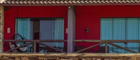 A two-story building with a red facade, solar panels on the roof, and a sign reading "Pier Beach Pousada Club Bar & Restaurant".