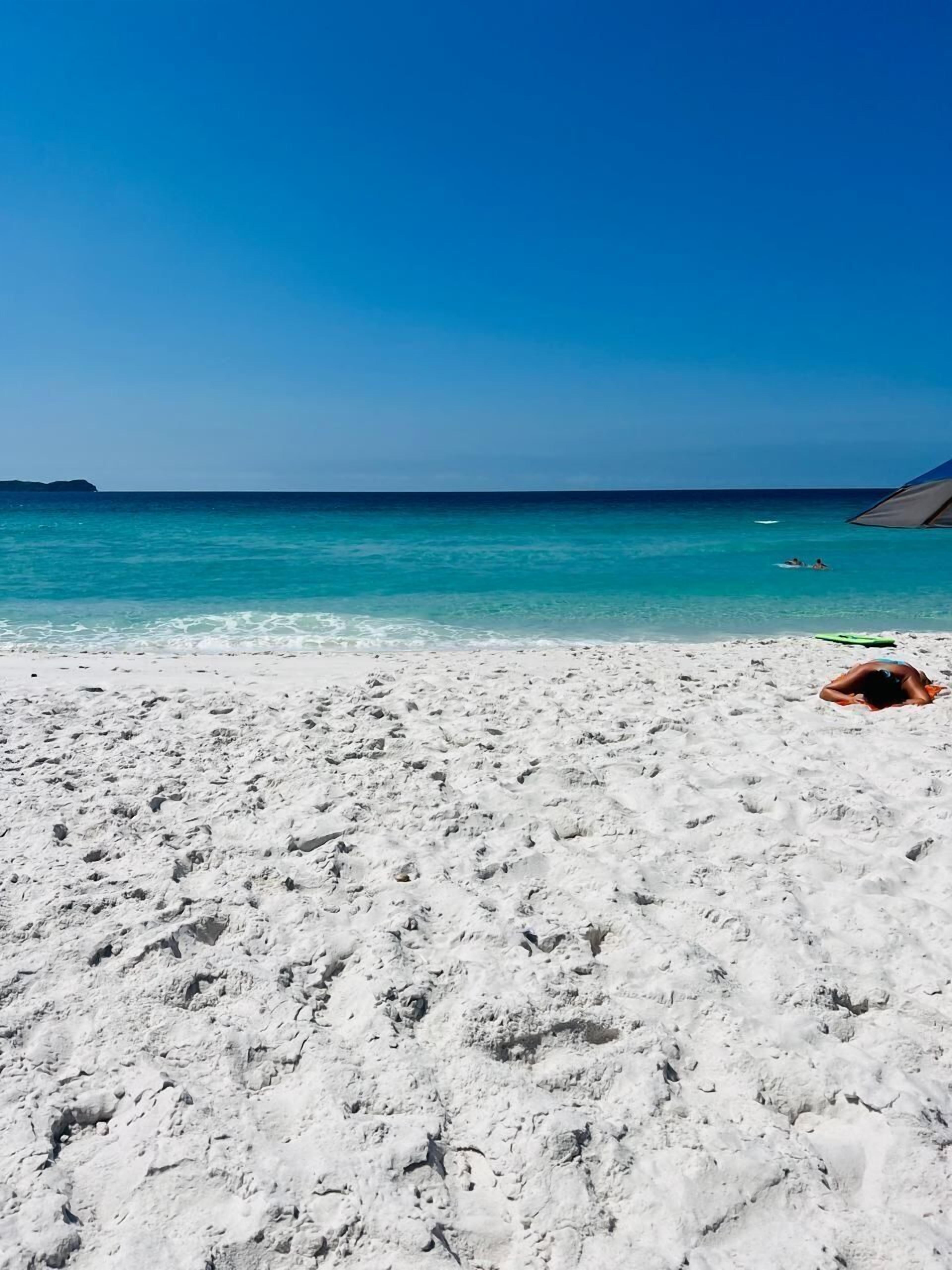 Am Strand, weißer Sandstrand, Sonnenschirme, Strandtücher