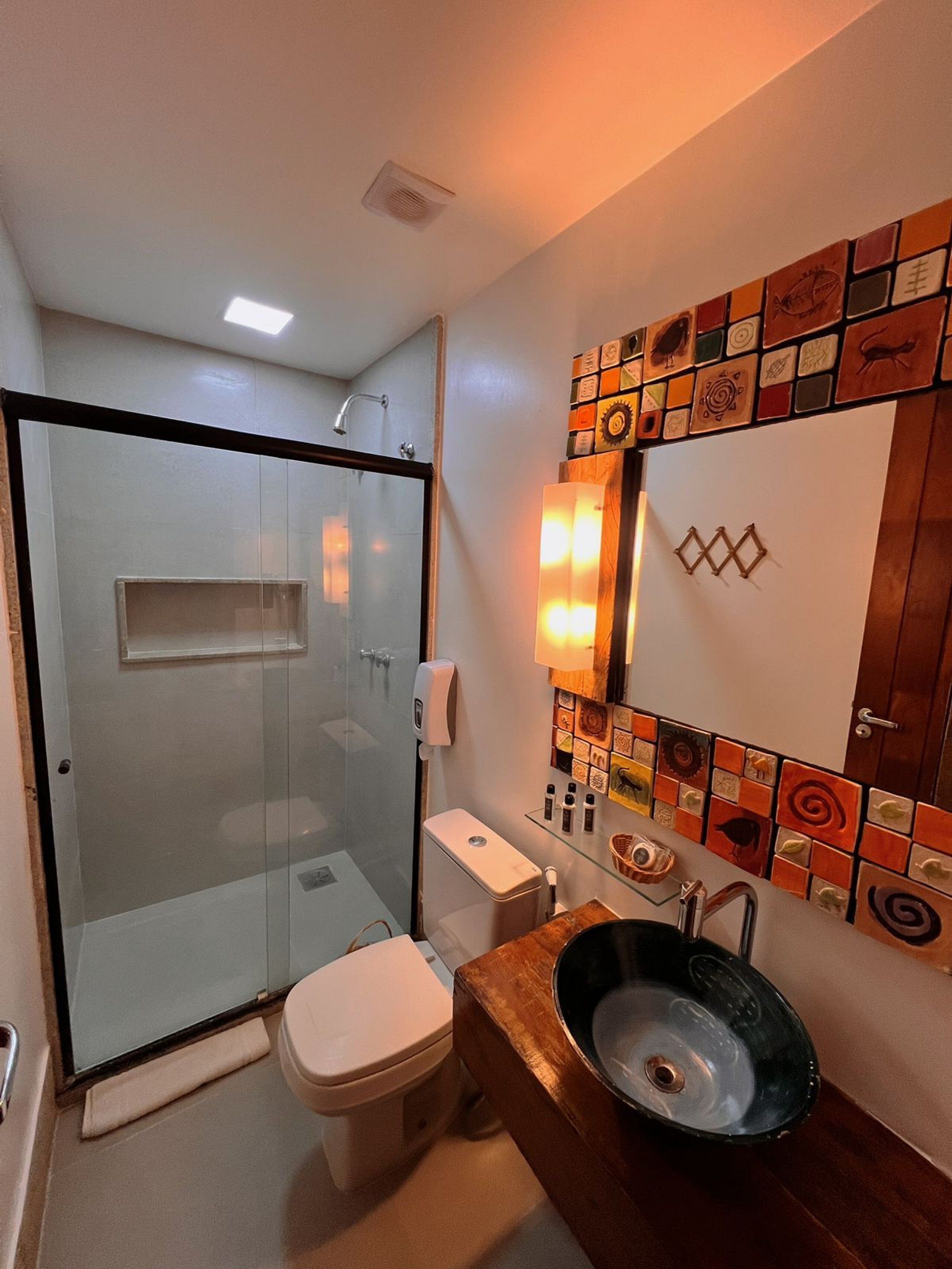 A modern bathroom with a glass-enclosed shower, a toilet, and a sink with a wooden countertop.