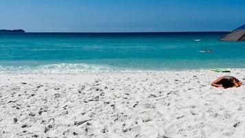 Sulla spiaggia, sabbia bianca, ombrelloni, teli da spiaggia