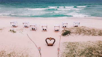 Rannalla, valkoista hiekkaa, aurinkovarjoja, rantapyyhkeitä