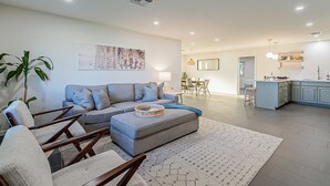 A modern living room with a grey sofa, wooden chairs, and a patterned rug. - Modern Oasis with Pool in the Valley of the Sun (Tempe)