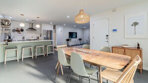 A modern kitchen with a central island, dining area with chairs, and a large wooden table. - Modern Oasis with Pool in the Valley of the Sun (Tempe)