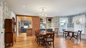 A spacious kitchen with a brick accent wall, wooden dining table, and chairs.