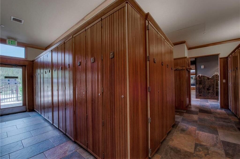 A corridor with wooden lockers and a checkered floor.