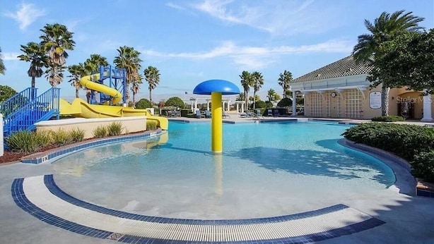 A swimming pool with a water slide, palm trees, and a building with a sign that reads "StellarMS". - Luxurious Villa - Near Disney - Golf Course (Davenport)